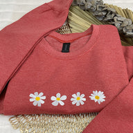 a red sweater with daisies on it sitting on a table