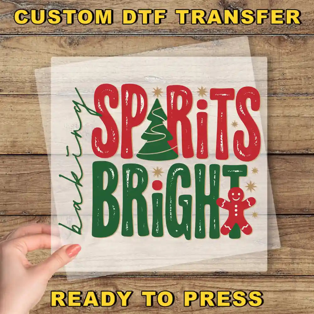 The image is a promotional poster for a custom DTSF (Digital Transfer System) transfer service. It features a hand holding a piece of paper with the text "SPIRITS BRIGHT" written on it, along with a gingerbread man symbol. The background is a wooden surface, and the text "CUSTOM DTSF TRANSFER" is displayed at the top, and "READY TO PRESS" is at the bottom.