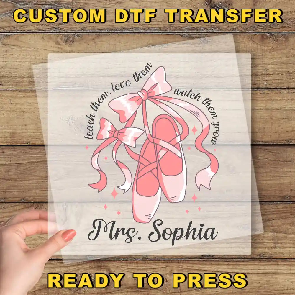 A hand is holding a transparent sheet with a design featuring a pair of pink ballet shoes and a bow, along with the text "Teach them, love them, watch them grow" and "Mrs. Sophia".