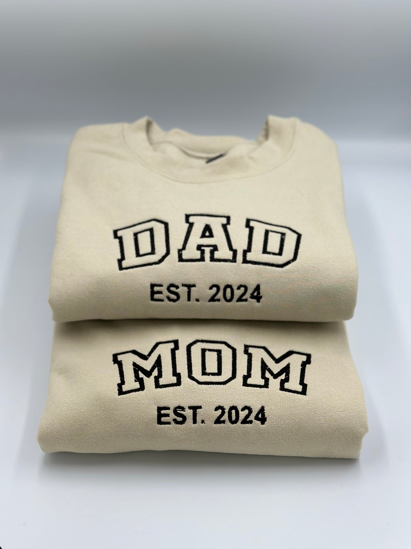 a pair of sweatshirts with the words dad and mom printed on them