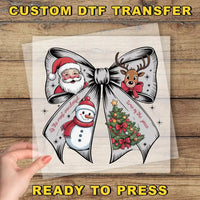 The image is a hand holding a clear plastic sheet with a decorative bow featuring illustrations of Santa Claus, a snowman, and a Christmas tree.