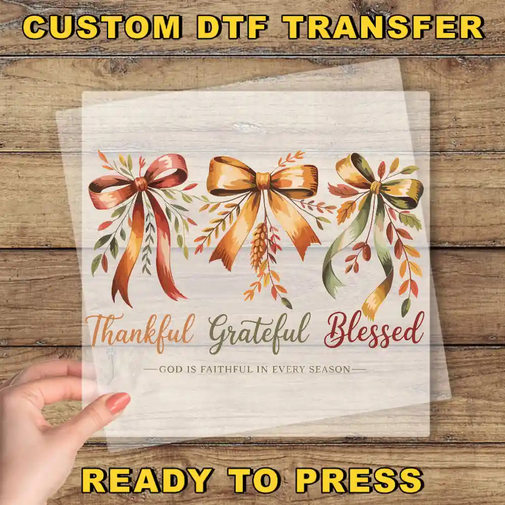 The image is a hand holding a transparent sheet with a design featuring three bows and the text "Thankful Grateful Blessed" written below them.