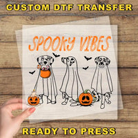 a hand holding a paper with a picture of three dogs in halloween costumes