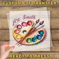 a person holding a piece of paper with paint and brushes on it