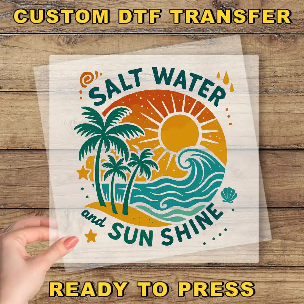 a hand holding a clear sheet with a vibrant, tropical-themed design on it. The design includes palm trees, a sun, and waves, conveying a sense of relaxation and enjoyment. The text "Salt Water and Sun Shine" is prominently displayed, suggesting a connection to the beach and the sun. The phrase "READY TO PRESS" is also visible, indicating that the image is ready to be printed or used.