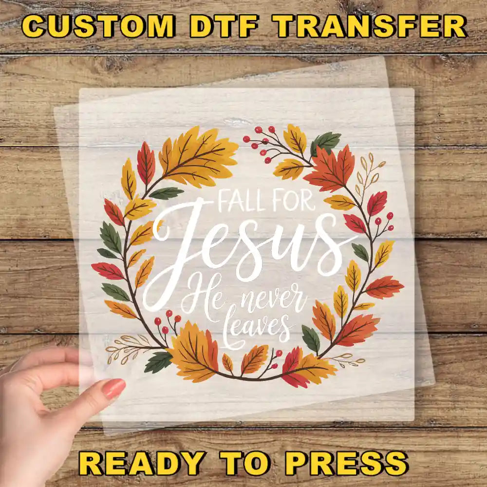 a hand holding a transparent sheet with a wreath design and text on it, placed on a wooden surface.