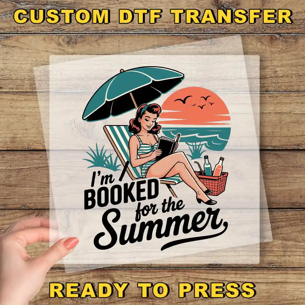 A hand holding a clear sheet with a vintage-style illustration of a woman sitting in a beach chair under an umbrella, reading a book, with a sunset in the background.