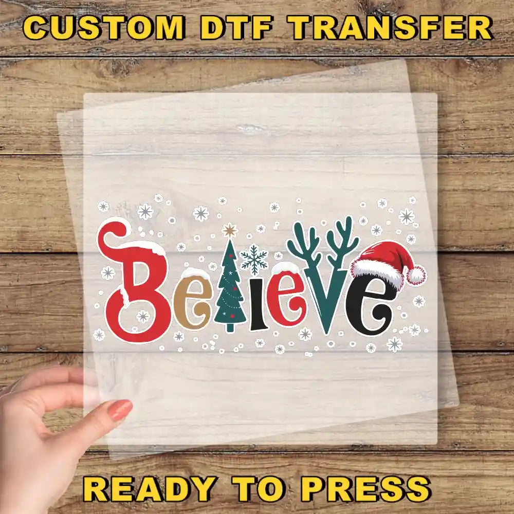 A hand holding a clear sheet with the word "Believe" written on it, surrounded by snowflakes and Christmas-themed decorations.