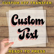 a hand holding a piece of paper with the text "Custom Text" written on it, against a wooden background.