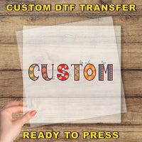 a hand holding a piece of paper with the word "CUSTOM" written on it, along with some colorful decorative elements.