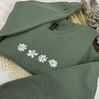 a green sweatshirt with daisies embroidered on it