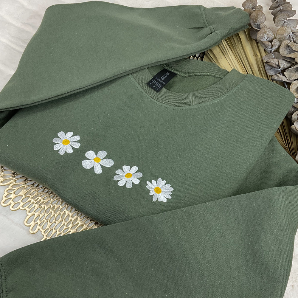 a green sweatshirt with daisies embroidered on it