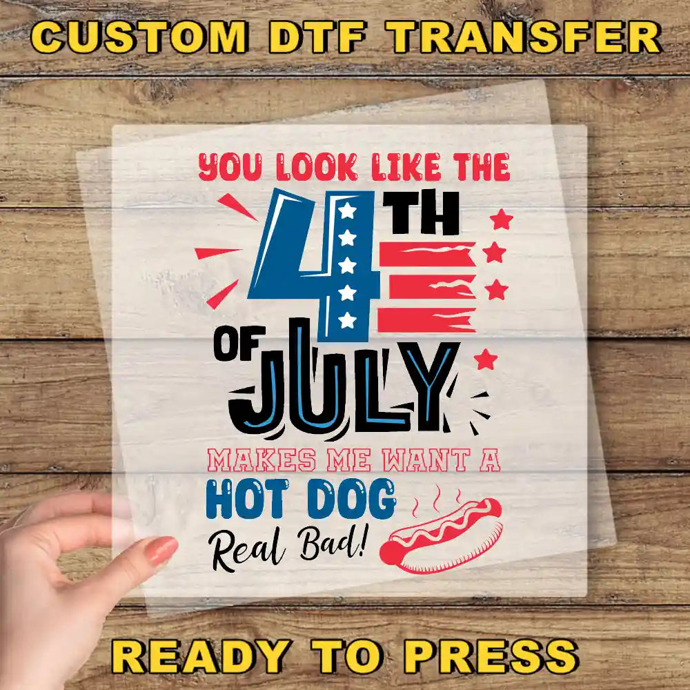 a hand holding a piece of paper with a patriotic design, including a hot dog and fireworks, along with text that says "You look like the 4th of July makes me want a hot dog real bad!".