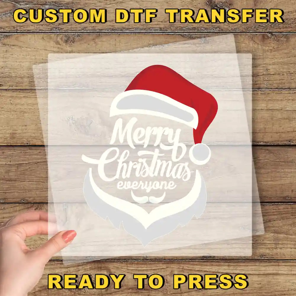 a hand holding a transparent sheet with a Santa Claus hat and the text "Merry Christmas everyone" printed on it.