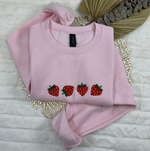 a pink shirt with three strawberries on it