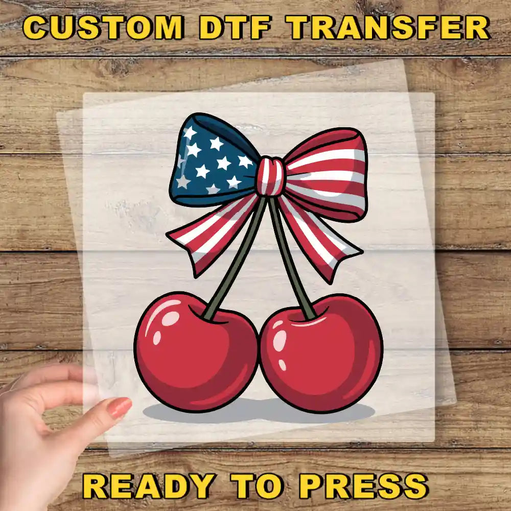 a hand holding a piece of paper with a bow and two cherries on it