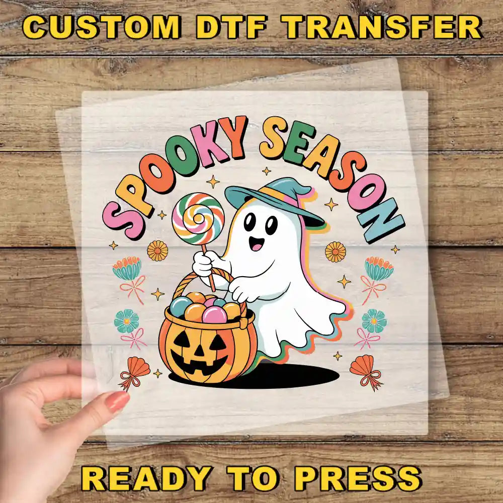 A hand is holding a clear sheet with a Halloween-themed graphic design featuring a ghost character holding a basket of candy and a jack-o-lantern.