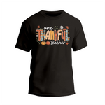 A black t-shirt with a colorful graphic design that says "One Thankful Teacher" in a stylized font.