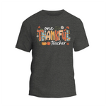A gray t-shirt with a graphic design featuring the text "One Thankful Teacher" surrounded by autumn-themed elements such as leaves, pumpkins, and flowers.