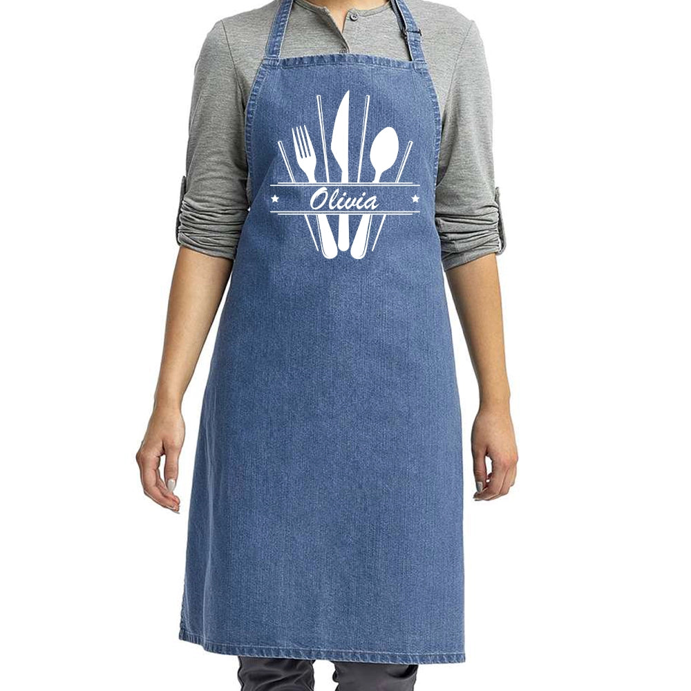 a woman wearing a denim apron with utensils on it