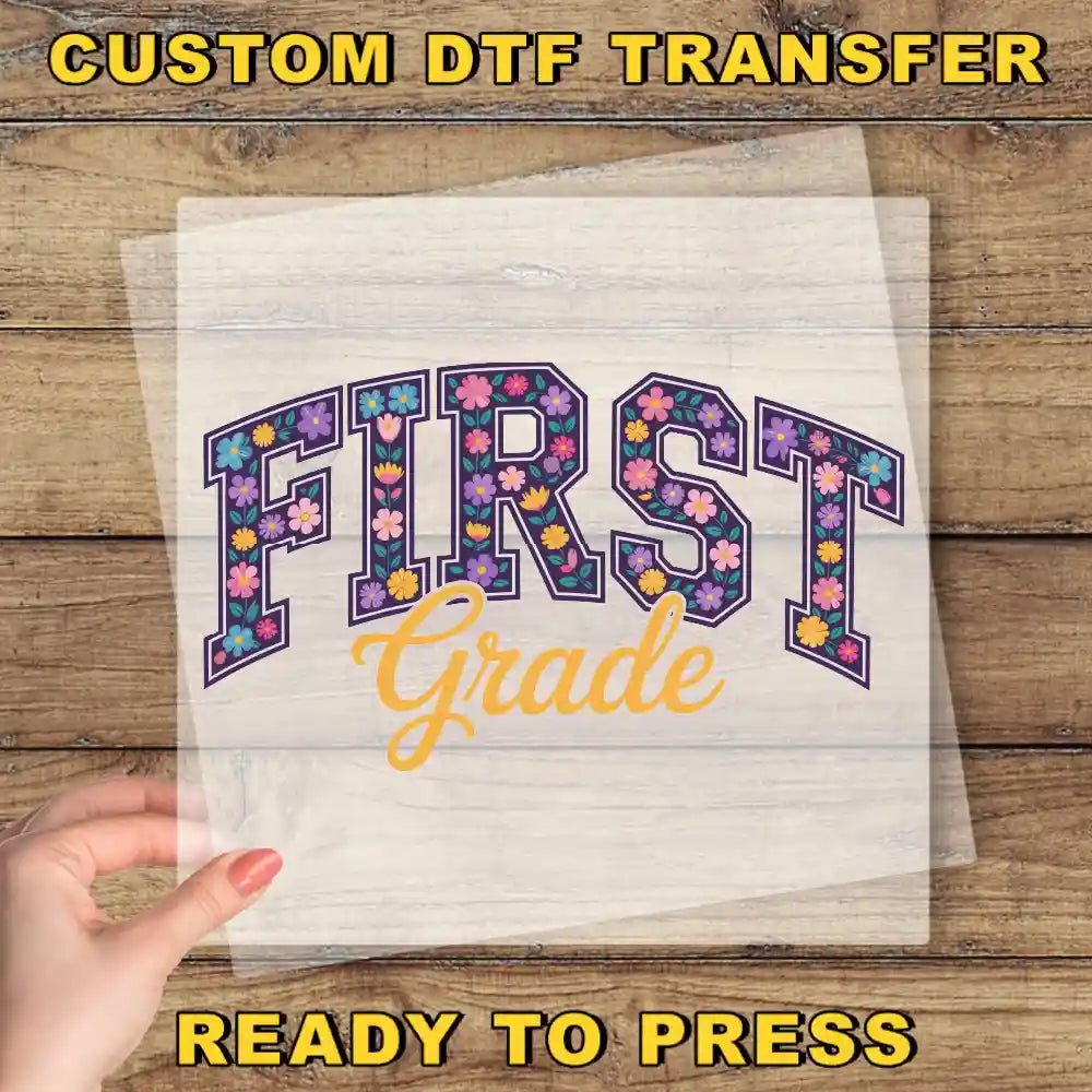 a hand holding a piece of paper with the text "FIRST Grade" printed on it, along with a "Custom Dtf Transfer" label.