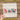 A hand is holding a clear sheet with the word "Believe" written on it, along with various Christmas-themed elements such as a snowman, reindeer, and a Santa hat.