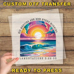 The image is a hand holding a transparent sheet with a colorful illustration of a sunrise over a body of water. The text on the sheet reads "His Mercies are new every morning" and "Lamentations 3:22-33".