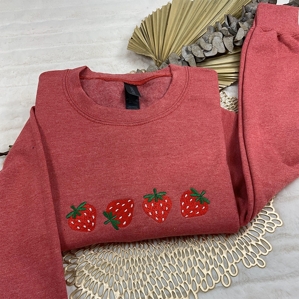 a red sweater with three strawberries embroidered on it