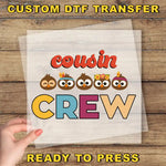 The image is a promotional poster for a custom DTSF (Digital Transfer Satellite) transfer service. It features a hand holding a clear sheet with the text "Cousin Crew" and a group of cartoon owl characters. The text is arranged in a playful and colorful manner, suggesting a fun and creative transfer service for families.