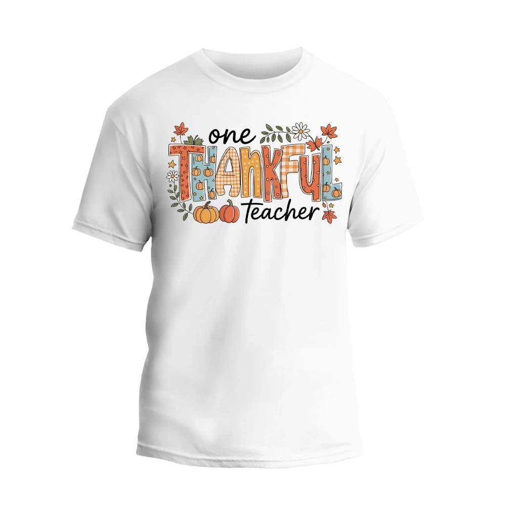 A white t-shirt with a graphic design featuring the text "One Thankful Teacher" surrounded by autumn-themed elements such as leaves, pumpkins, and flowers.