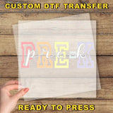 The image is a promotional image for a custom DTF (Digital Transfer Factory) transfer service. It features a hand holding a clear sheet with the word "PREK" printed on it, along with the text "CUSTOM DTF TRANSFER" and "READY TO PRESS" at the bottom.