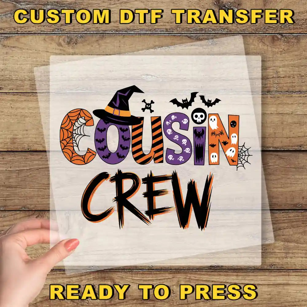 a hand holding a piece of paper with the text "Cousin Crew" written on it, along with various Halloween-themed decorations such as bats, skulls, and a spider web.