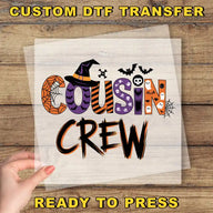 a hand holding a piece of paper with the text "Cousin Crew" written on it, along with various Halloween-themed decorations such as bats, skulls, and a spider web.
