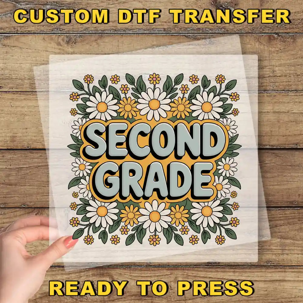 a hand holding a piece of paper with a floral design and the text "Second Grade" printed on it.