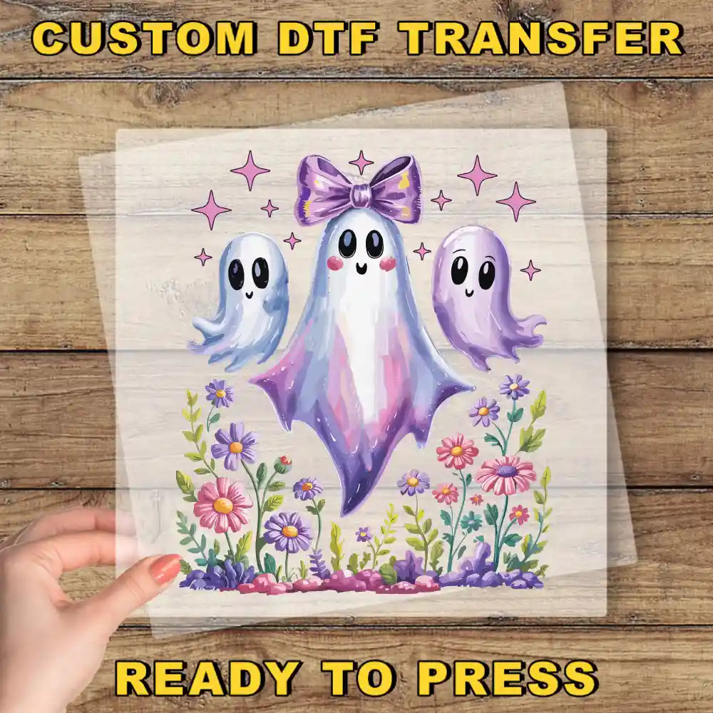 a hand holding a transparent sheet with a colorful illustration of three ghostly figures surrounded by flowers and plants.