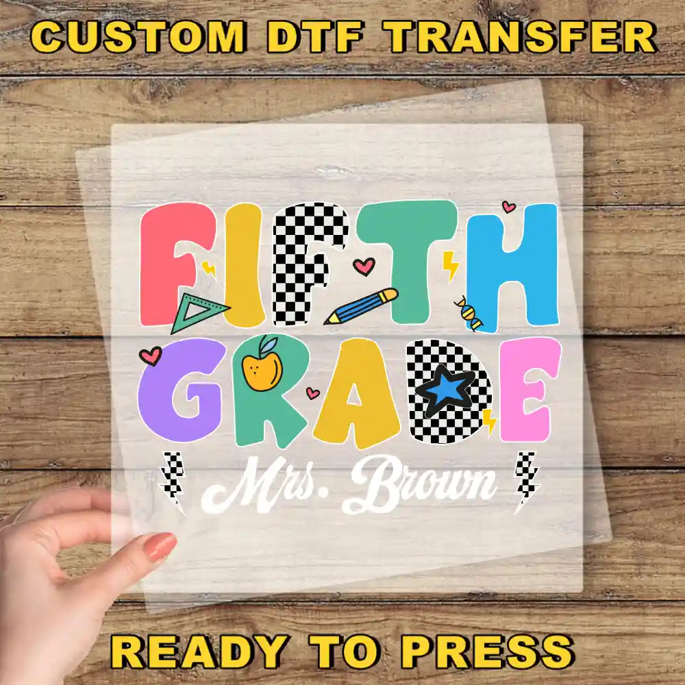A hand is holding a transparent sheet with the text "Fifth Grade Mrs. Brown" printed on it, along with various colorful and playful illustrations.