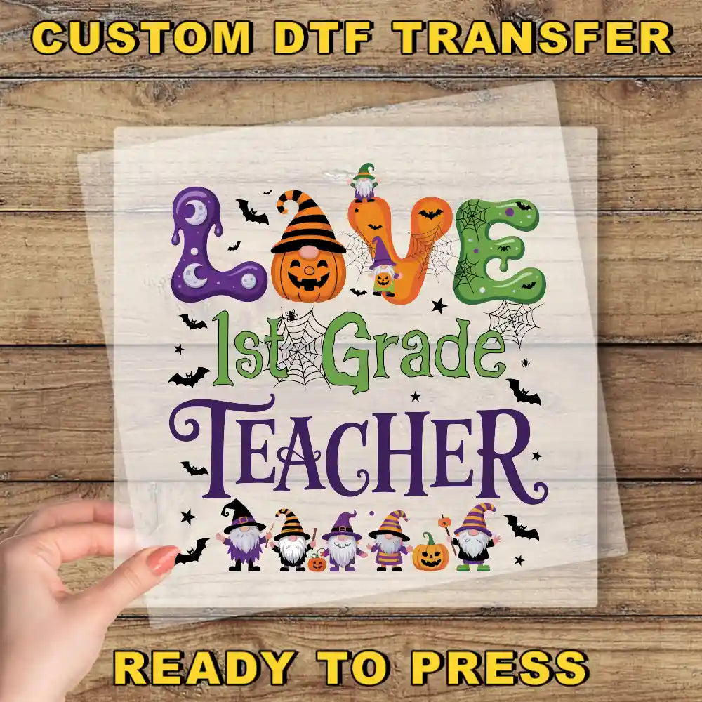 The image is a Halloween-themed graphic with the text "LOVE 1st Grade TEACHER" and various Halloween-related elements such as bats, pumpkins, and a spider web.