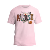 A pink t-shirt with the word "NURSE" written in a creative and colorful design, featuring a spider web, bats, a pumpkin, and other Halloween-themed elements.