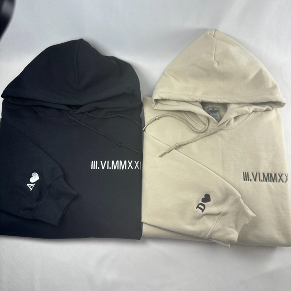 two hoodies laying on top of a bed next to each other