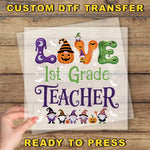 The image is a Halloween-themed poster with the text "LOVE 1st Grade TEACHER" and various Halloween-themed illustrations, including a pumpkin, spider, and gnome characters.