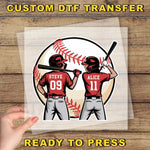 A hand is holding a clear plastic sheet with a cartoon illustration of two baseball players, Steve and Alice, standing in front of a baseball.