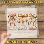 The image is a hand holding a transparent sheet with a design featuring three bows and the text "Thankful Grateful Blessed" written below them.