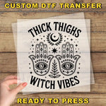 a hand holding a paper with the words trick thighs witch vibes ready to press