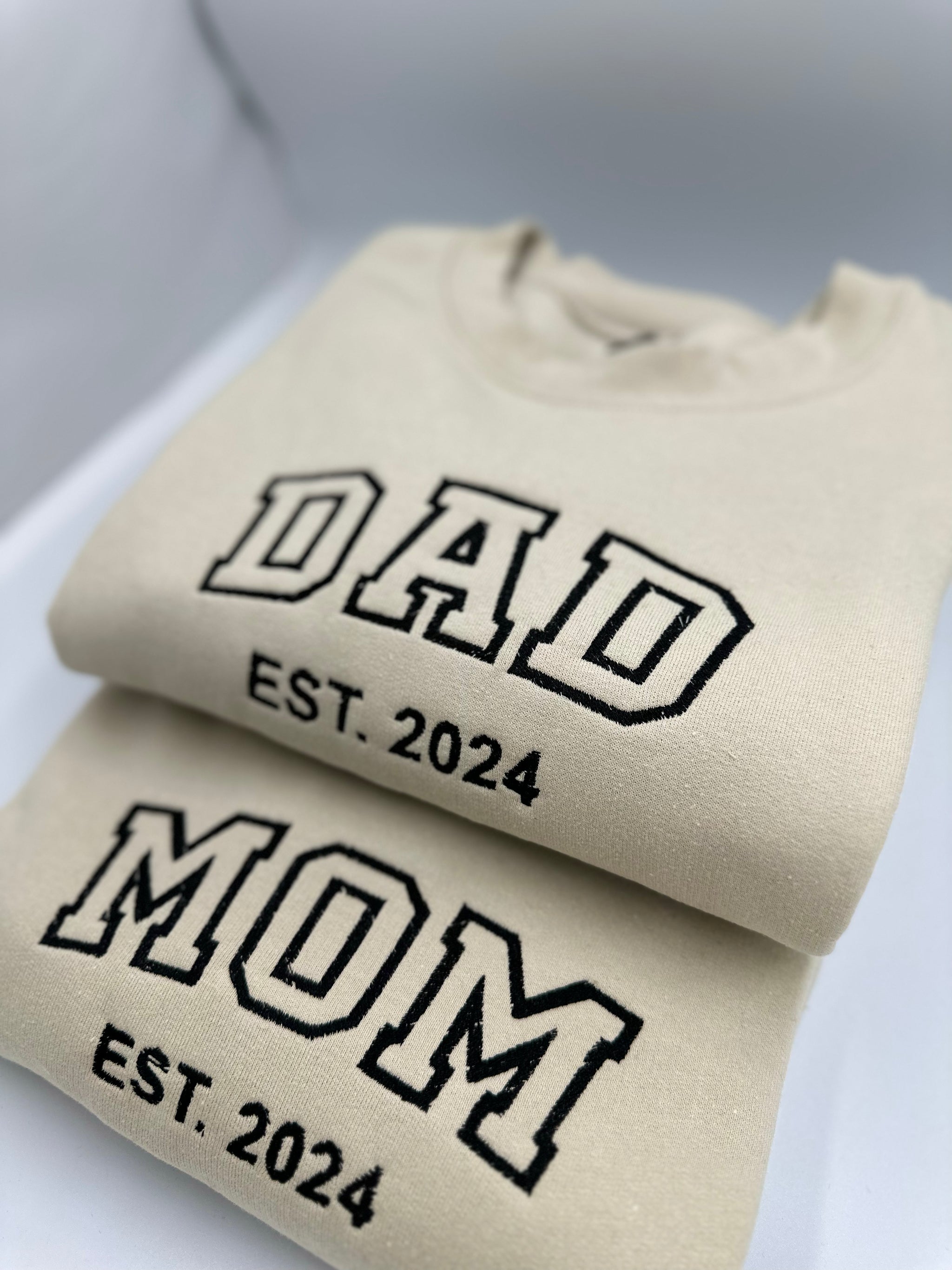 a pair of t - shirts with the words dad and mom printed on them