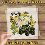 A hand is holding a clear sheet with a colorful graphic design featuring a monster truck, checkered flags, and stars. The text "KINDERGARTEN" is prominently displayed in the center of the design.
