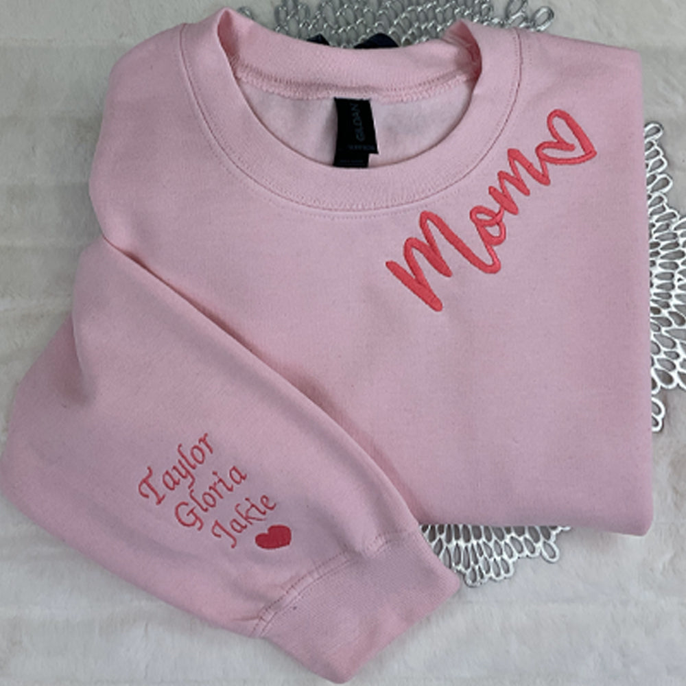 a pair of pink sweaters sitting on top of a bed
