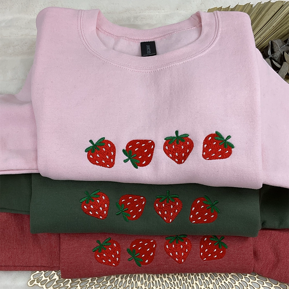 a pile of different colored shirts with strawberries on them