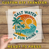 a hand holding a clear sheet with a vibrant, tropical-themed design on it. The design includes palm trees, a sun, and waves, conveying a sense of relaxation and enjoyment. The text "Salt Water and Sun Shine" is prominently displayed, suggesting a connection to the beach and the sun. The phrase "READY TO PRESS" is also visible, indicating that the image is ready to be printed or used.