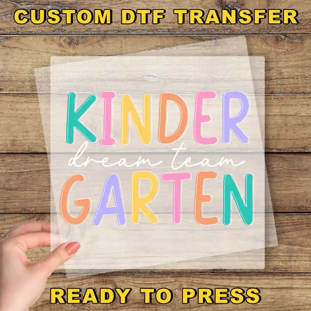 a hand holding a piece of paper with the words kinder dream team written on