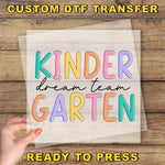 a hand holding a piece of paper with the words kinder dream team garter